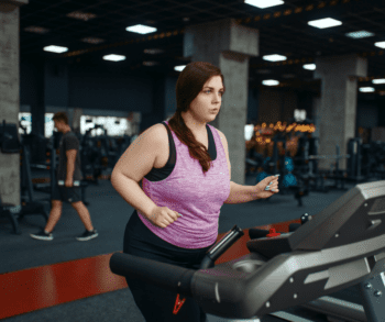 Overweight girl jogging on a treadmill in a gym