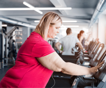 Overweight woman in the gym standing on a treadmill 